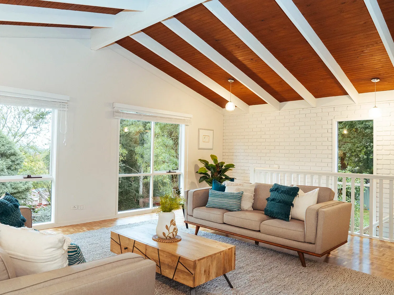 A bright living room beneath exposed timber ceiling members.