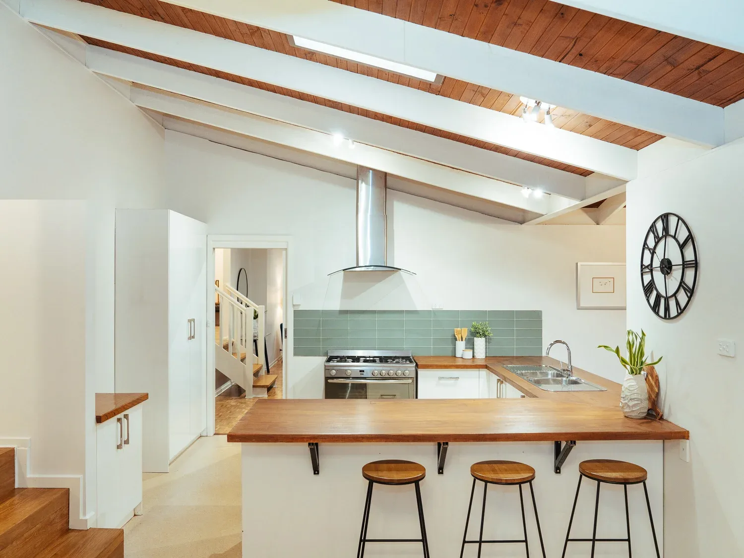 The pale kitchen beneath timber structural lines.
